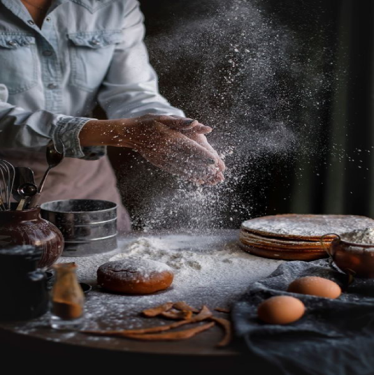 A baker dusting flour over dough.