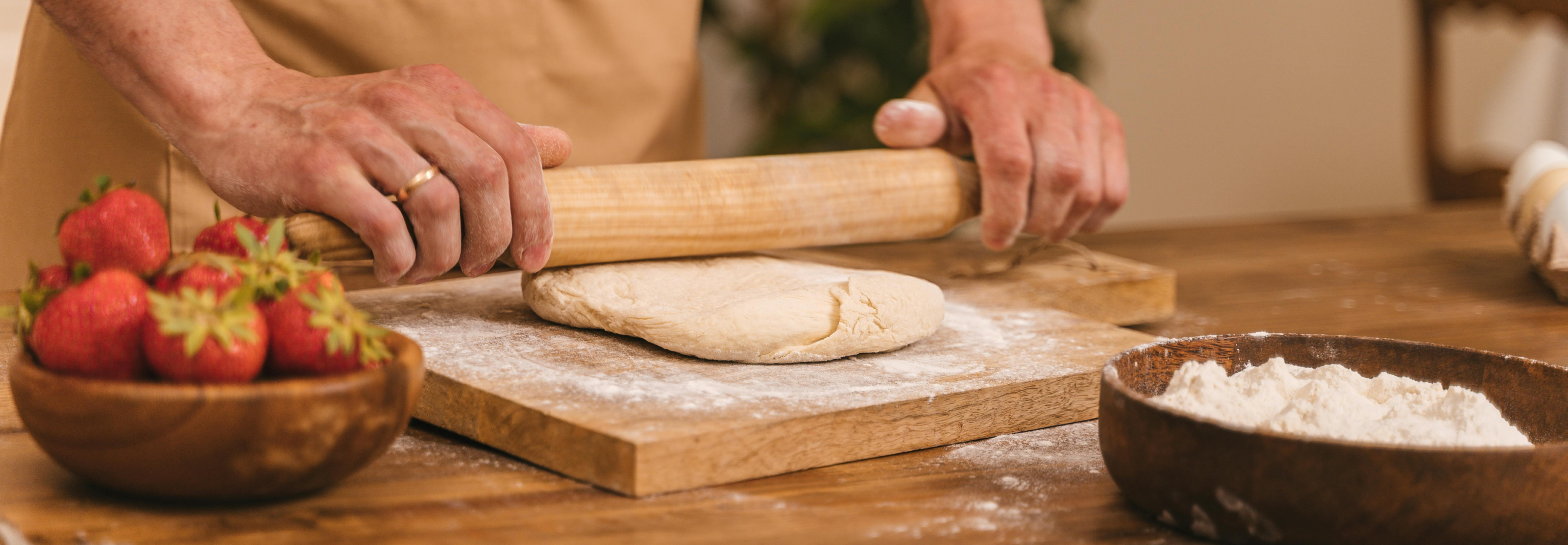 Người thợ làm bánh đang cán bột với dâu tây bên cạnh